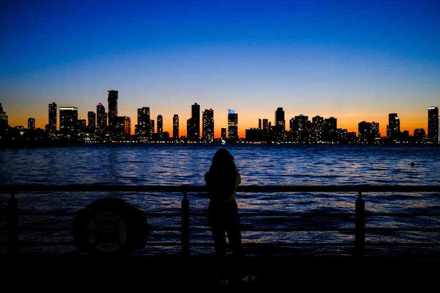 A woman takes photographs of the Jersey City skyline in New Jersey, from the Manhattan borough of New York City at dusk on 23 August 2025. (Charly Triballeau/AFP)
