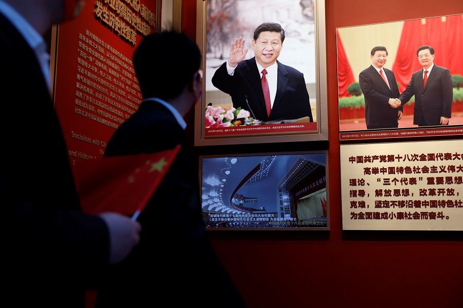 A man holds a Chinese flag near images of Chinese President Xi Jinping displayed at the Museum of the Communist Party of China in Beijing, China, 11 November 2021. (Carlos Garcia Rawlins/Reuters)
