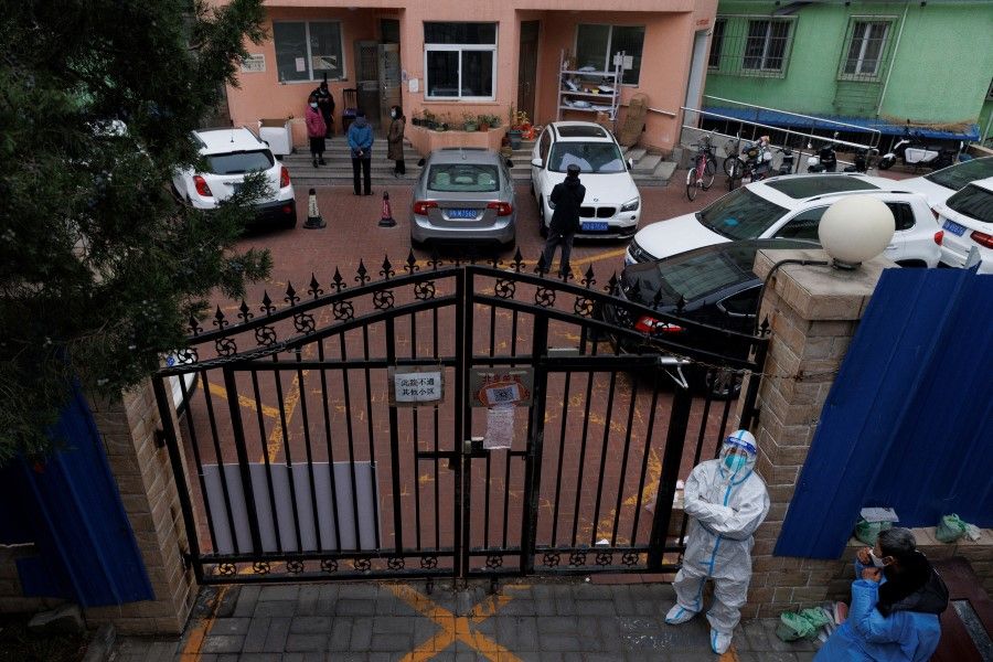 A pandemic prevention worker in a protective suit keeps watch at at residential compound after it was locked down as outbreaks of Covid-19 continue in Beijing, 18 November 2022. (Thomas Peter/Reuters)