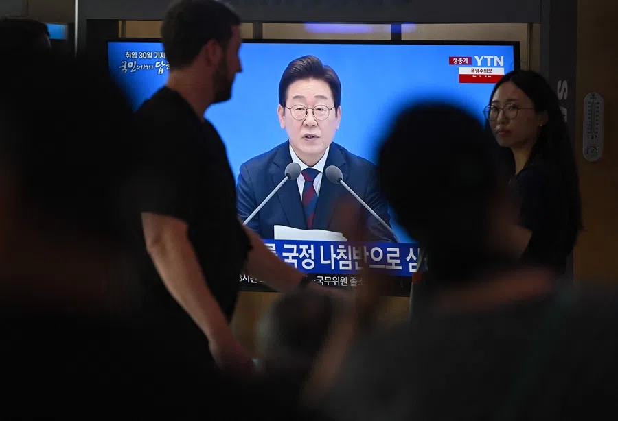 People watch a television screen showing a live broadcast of South Korea’s President Lee Jae-myung speaking during a press conference to mark his first 30 days in office, at a train station in Seoul on 3 July 2025.
