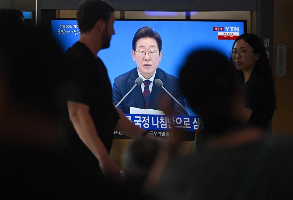 People watch a television screen showing a live broadcast of South Korea’s President Lee Jae-myung speaking during a press conference to mark his first 30 days in office, at a train station in Seoul on 3 July 2025. (Jung Yeon-je/AFP)
