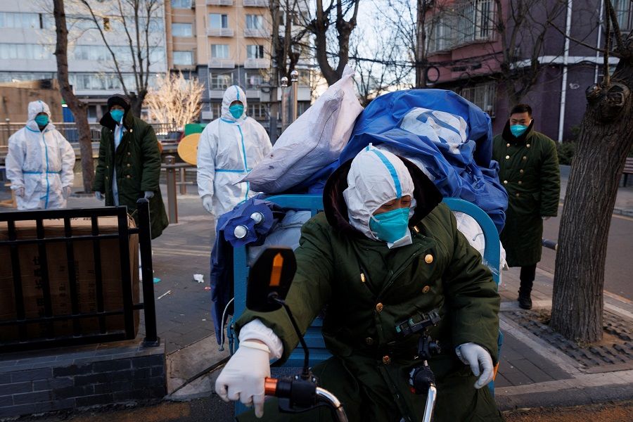 Pandemic control workers in protective suits remove tents that served as their living quarters in a neighbourhood that used to be under lockdown in Beijing, China, 10 December 2022. (Thomas Peter/Reuters)