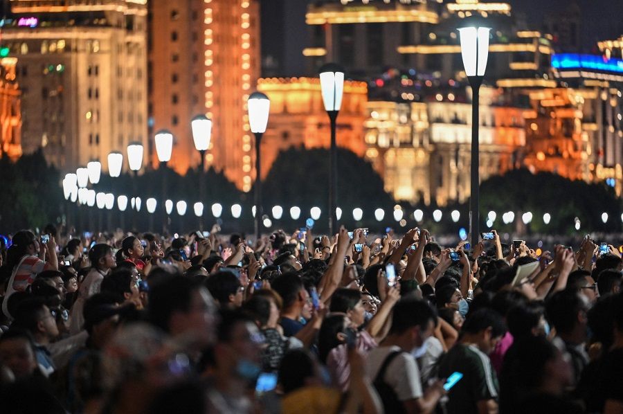 Spectators view a light show on the Bund promenade in Shanghai, China on 1 July 2021, as the country marks the 100th anniversary of the founding of China's Communist Party. (Hector Retamal/AFP)