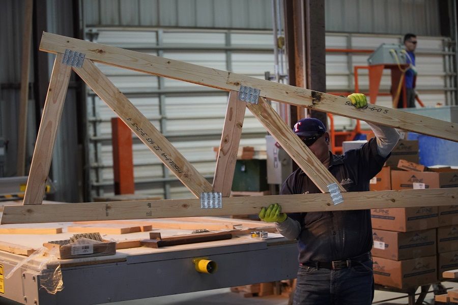 A worker carries a finished truss for a home at Wasatch Truss on 12 May 2021 in Spanish Fork, Utah, US. (George Frey/Getty Images/AFP)