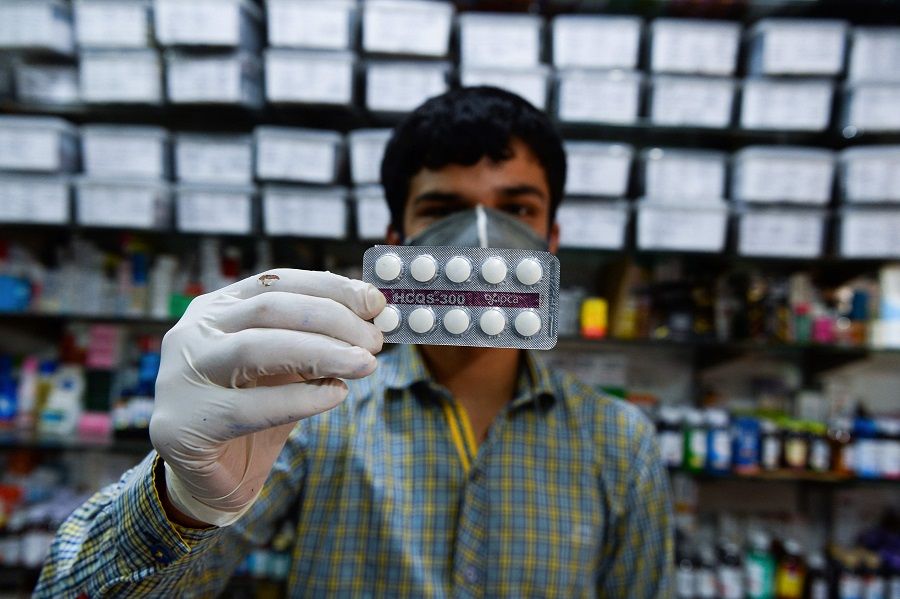 This photo taken on 27 April 2020 shows a pharmacy employee displaying hydroxychloroquine tablets in his store in New Delhi. (Photo by Sajjad Hussain/AFP)