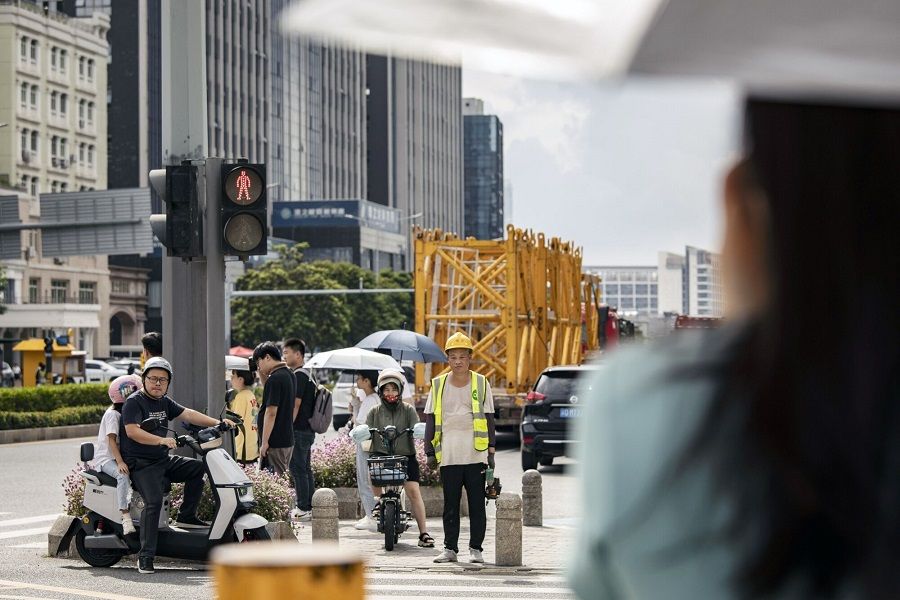 Pedestrians wait to cross a road in Shenzhen, China, on 9 August 2023. (Qilai Shen/Bloomberg)