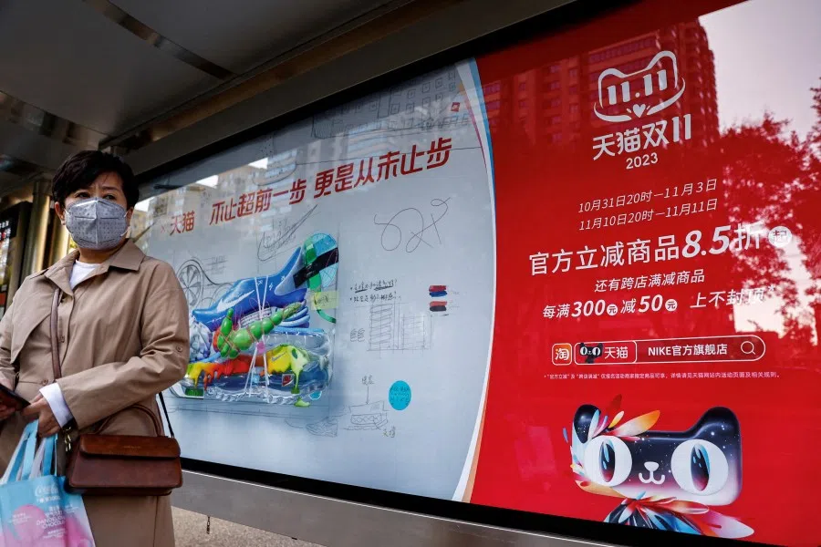 A woman stands near an Alibaba's advertisement promoting Singles Day shopping festival, at a bus stop in Beijing, China, on October 26, 2023. (Tingshu Wang/Reuters)