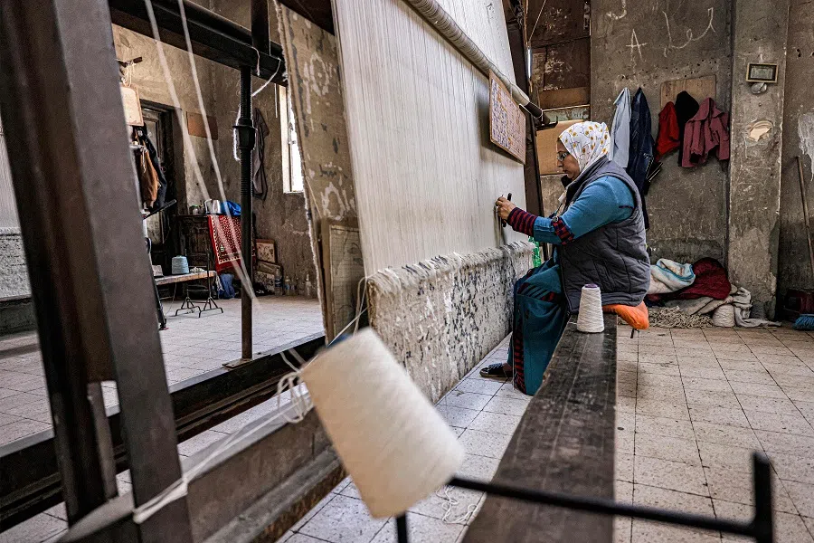 In this picture taken on 20 February 2023, a worker operates a loom while fabricating a rug at the Kahhal Looms handmade rugs workshop in the Basateen district of Cairo, Egypt. (Khaled Desouki/AFP)