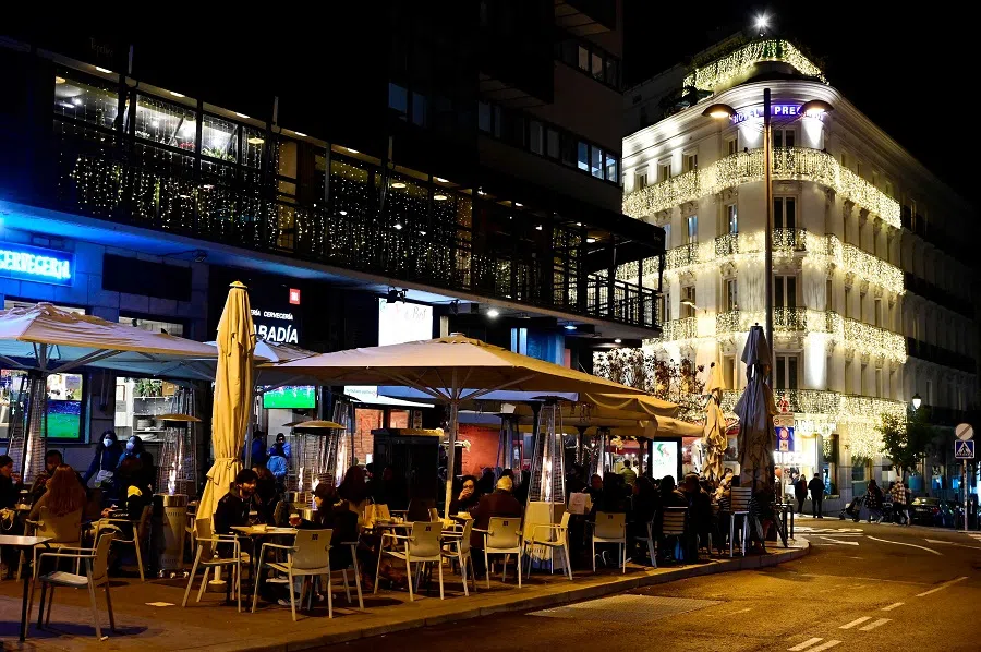 People sit at a cafe terrace, next to Christmas lights in the streets of Madrid, Spain, on 22 December 2021. (Javier Soriano/AFP)