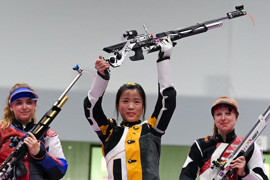 China's Yang Qian celebrates on the podium between Russia's Anastasiia Galashina (left) and Switzerland's Nina Christen after winning the women's 10m air rifle final during the Tokyo 2020 Olympic Games at the Asaka Shooting Range in the Nerima district of Tokyo on 24 July 2021. (Tauseef Mustafa/AFP)