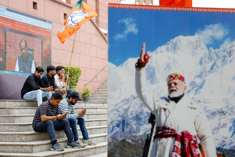 People sit near an image of Indian Prime Minister Narendra Modi at the Bharatiya Janata Party (BJP) headquarters in New Delhi, India, on 4 June 2024. (Adnan Abidi/Reuters)