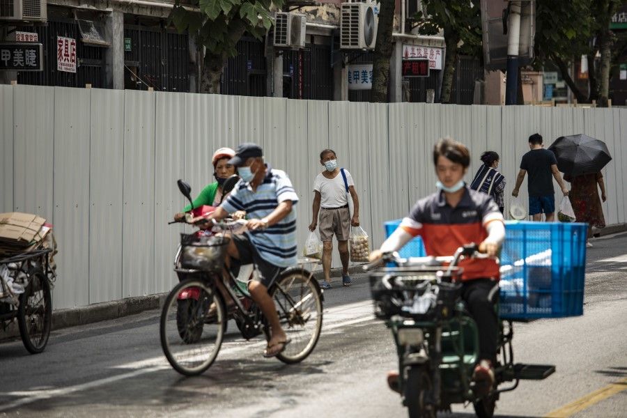 Pedestrians pass fencing surrounding a residential neighborhood placed under lockdown due to Covid-19 in Shanghai, China, on 6 July 2022. (Qilai Shen/Bloomberg)