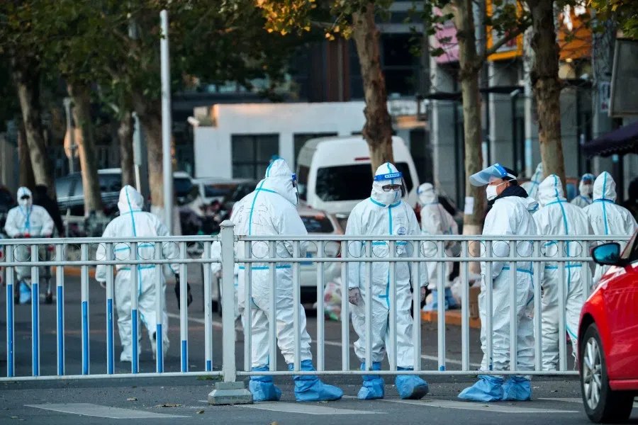 Security personnel in protective suits guard the perimeters of a residential compound that was locked down after a local outbreak of the coronavirus disease (Covid-19) in Beijing, China, 11 November 2021. (Thomas Peter/Reuters)