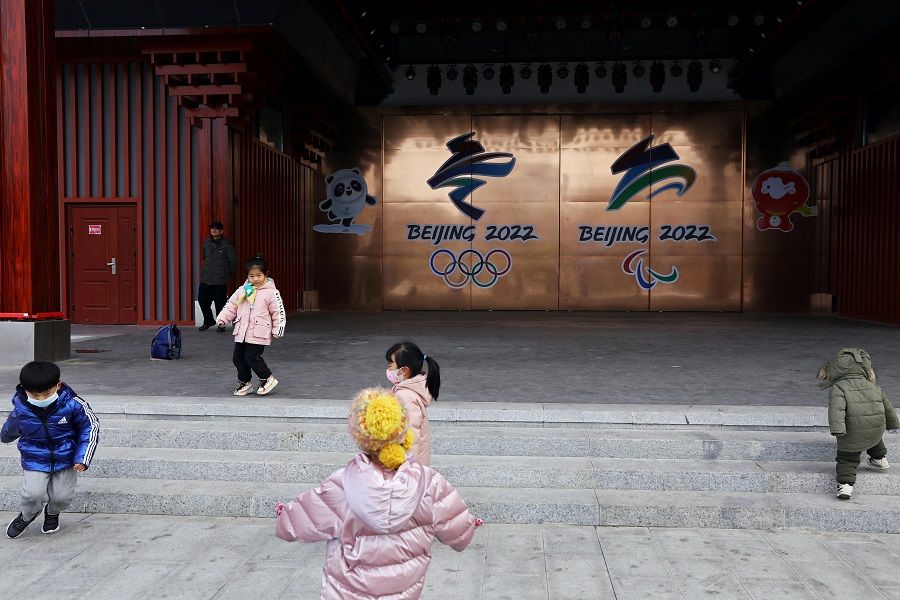 Children play in front of emblems of the Beijing 2022 Winter Olympics and Paralympics at a park in Beijing, China, 26 January 2022. (Tingshu Wang/Reuters)