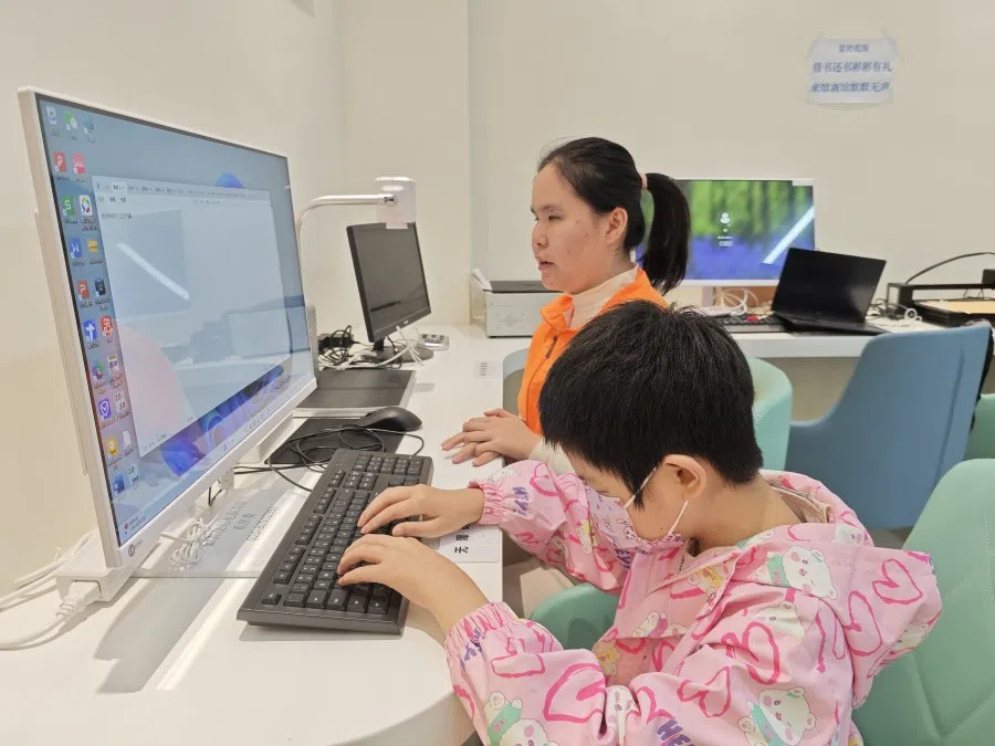 Feifei teaches Liang Minni to use the computer.
