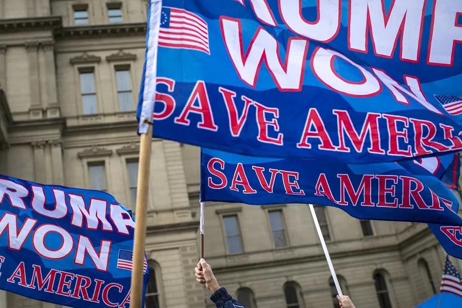 People raise flags in support of Donald Trump in the air at the Michigan State Capitol on 12 October 2021 in Lansing, Michigan, US. (Nic Antaya/Getty Images/AFP)