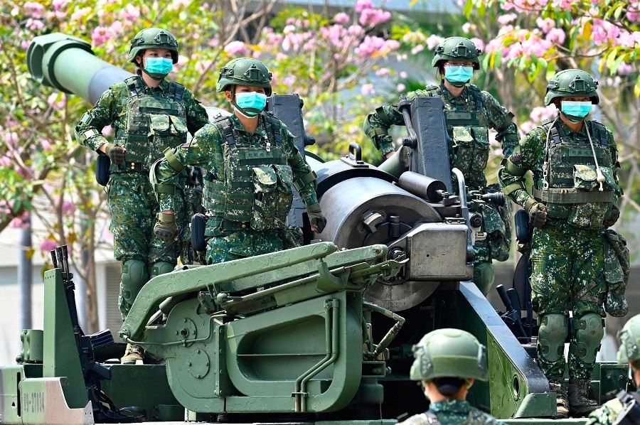 Female soldiers wearing face masks amid the Covid-19 pandemic stand in formation on a US-made M110A2 self-propelled howitzer during Taiwan President Tsai Ing-wen's visit to a military base in Tainan, Taiwan, on 9 April 2020. (Sam Yeh/AFP)