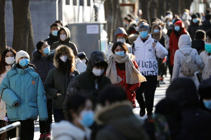 People wearing face masks walk along Nanluoguxiang alley, in Beijing, China, 16 January 2021. (Tingshu Wang/Reuters)