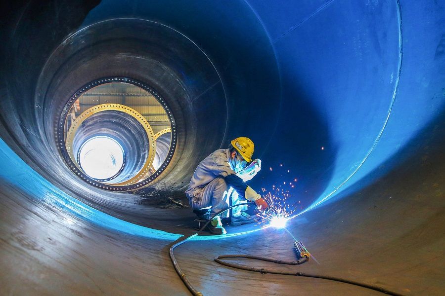 An employee works on a wind turbine tower at a factory in Lianyungang, Jiangsu province, China, on 31 May 2023. (AFP)