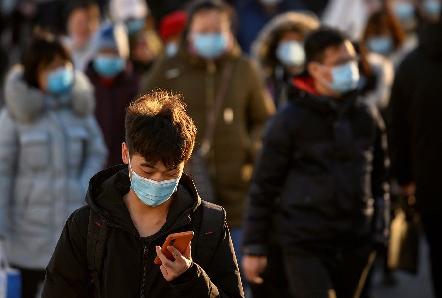 People wearing face masks walk along a street during a rush hour in Beijing on 16 December 2020. (Noel Celis/AFP)
