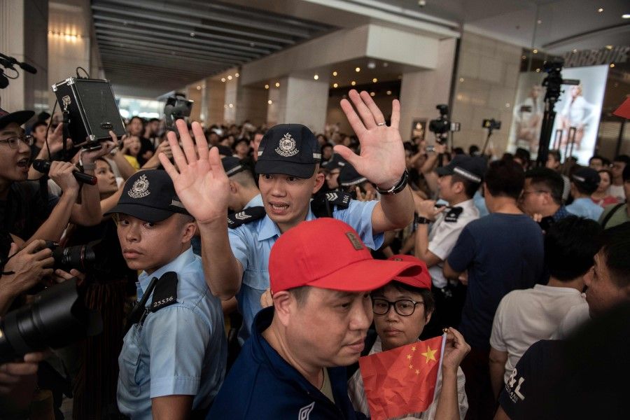A Hong Kong police officer tries to calm a mixed crowd of pro-Beijing and pro-democracy supporters. (Nicolas Asfouri/AFP)