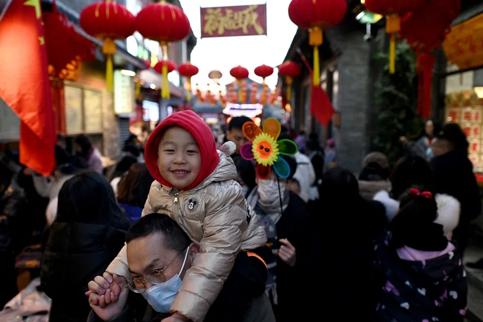 People walk through an alley decorated with traditional lanterns near Houhai lake in Beijing, China, on 2 February 2022. (Noel Celis/AFP)