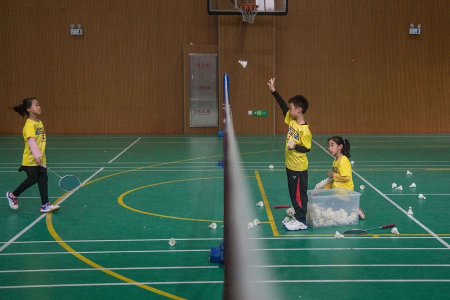 This photo taken on 10 December 2021 shows children taking part in a badminton class at a combined primary-middle school in Shanghai, China. (Jessica Yang/AFP)