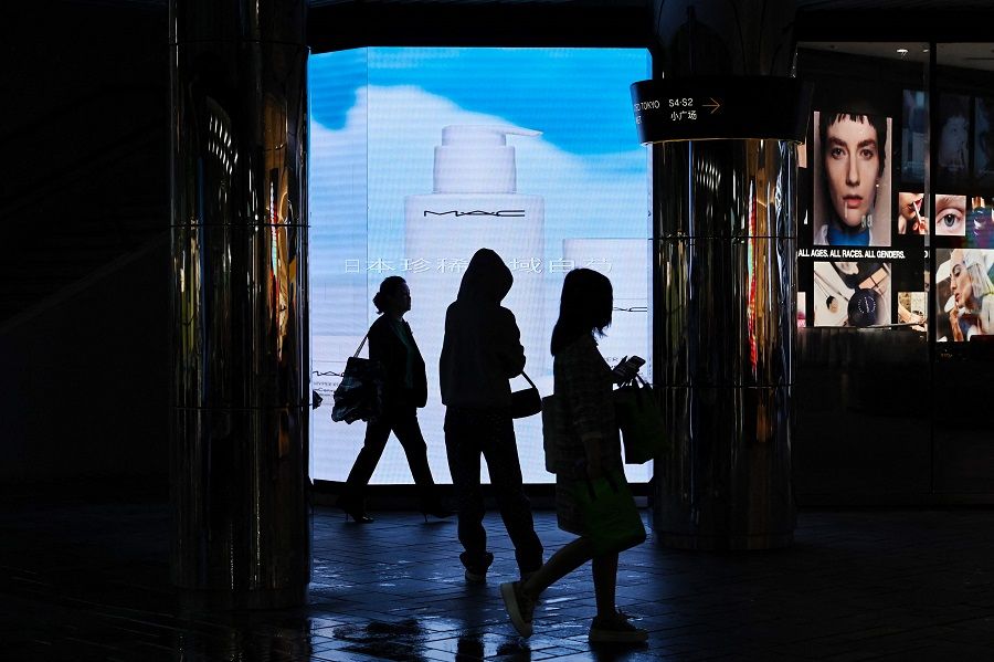 People walk past a makeup store at a shopping mall in Beijing, China, on 12 May 2023. (Greg Baker/AFP)