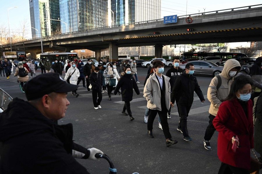 People cross a road in the central business district in Beijing on 16 December 2021. (Greg Baker/AFP)