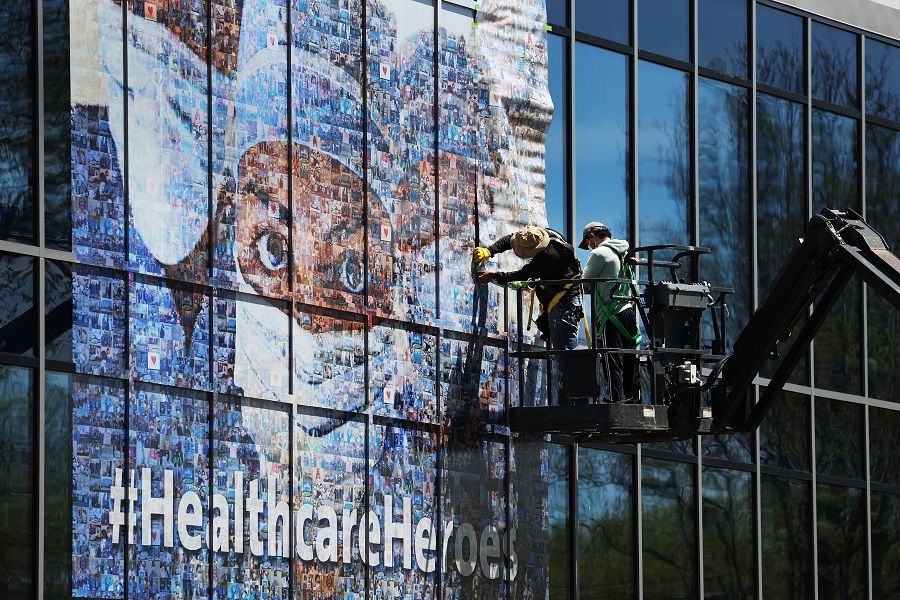 Workers put up a mural on a Northwell Healthcare building featuring healthcare workers who are on the frontlines during the Covid-19 pandemic on 5 May 2020 in New Hyde Park, New York. (Al Bello/Getty Images/AFP)