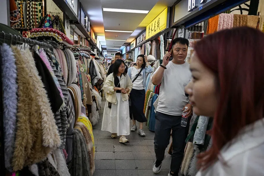 People walk in a textile market in Shaoxing, in China’s eastern Zhejiang province on 9 May 2025. (Greg Baker/AFP)