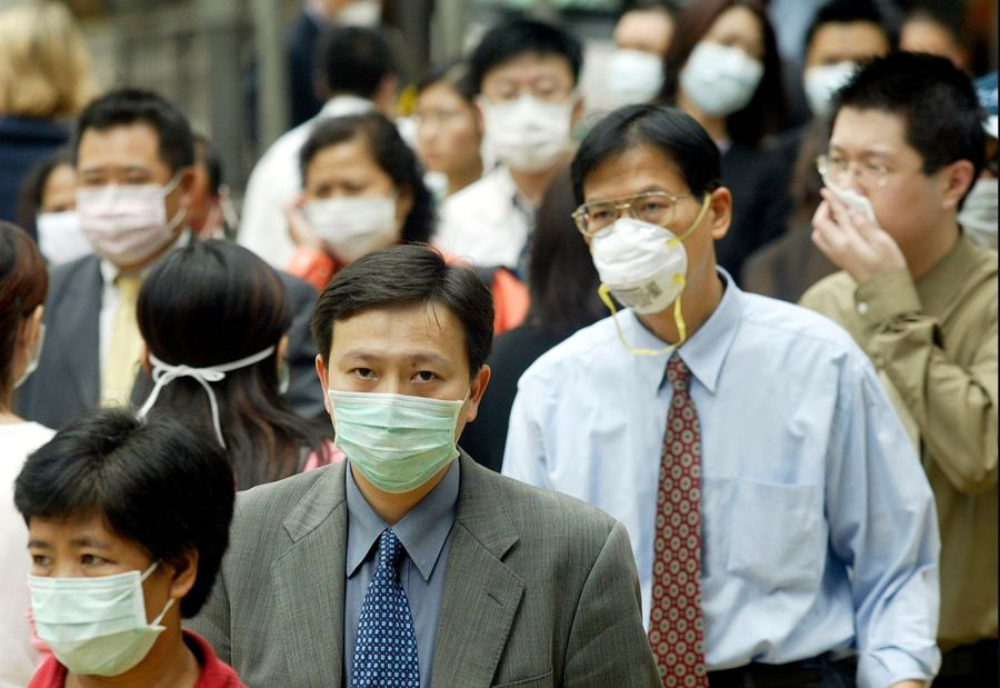 This file photo taken on 31 March 2003 shows pedestrians wearing masks on the street to protect against the SARS virus in Hong Kong. (Peter Parks/AFP)