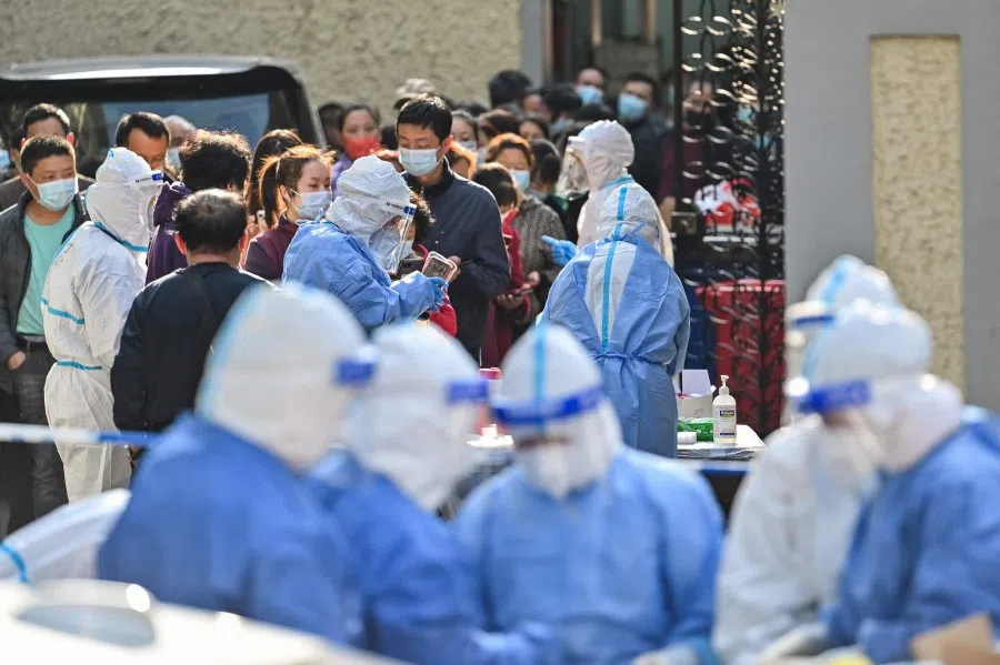 Health workers wearing protective gear prepare equipment before testing people for the Covid-19 coronavirus at a residential compound in Shanghai on 23 March 2022. (Hector Retamal/AFP)