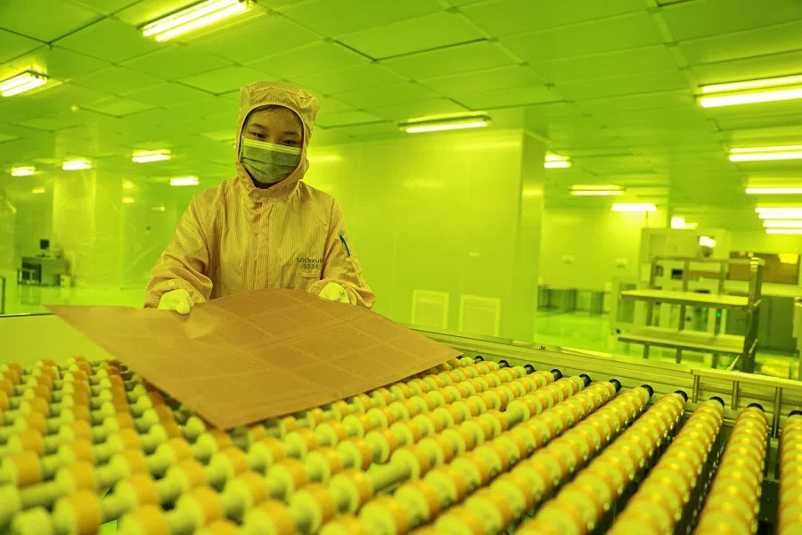 An employee works in a specially-lit area on a production line that produces printed circuit boards (PCB) for export at a factory in Jiujiang, in central China’s Jiangxi province on 24 July 2024. (AFP)