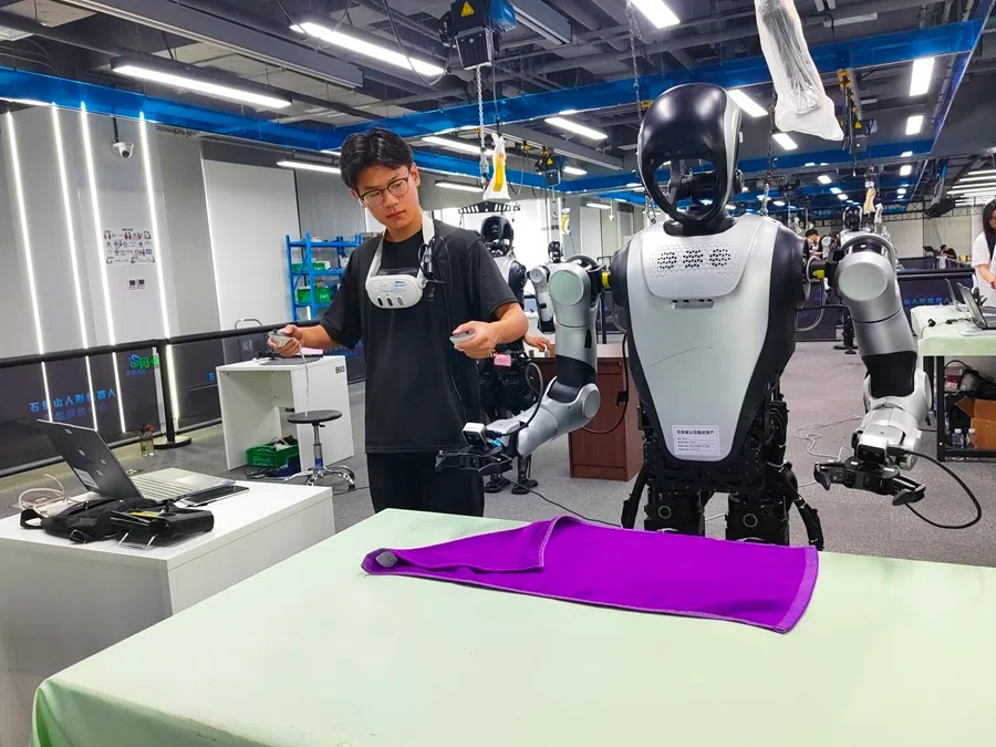 Data trainers at the Beijing Shijingshan Humanoid Robot Data Training Centre teach robots to fold cleaning cloths on 13 August 2026.