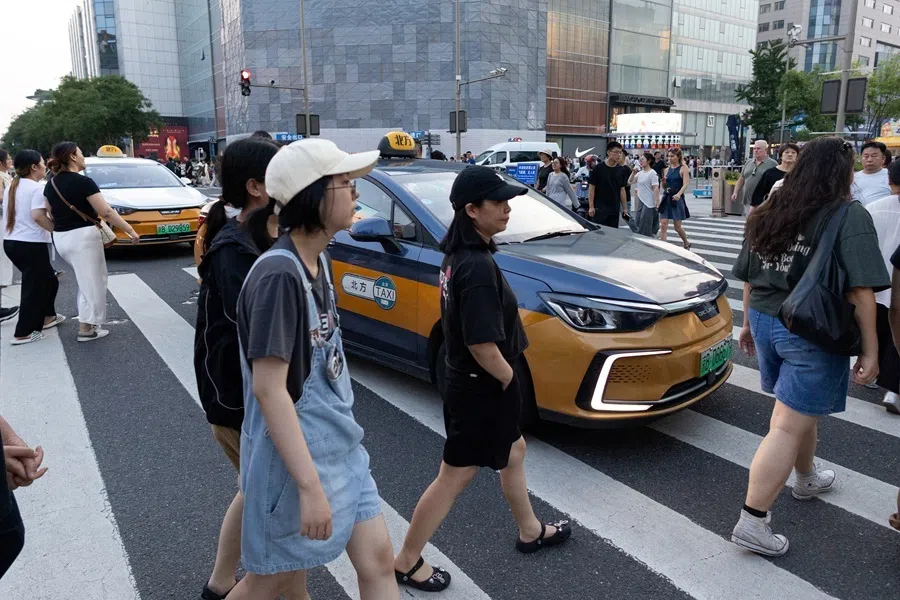 People cross the road next to taxi cars in Beijing, China, 8 July 2026.