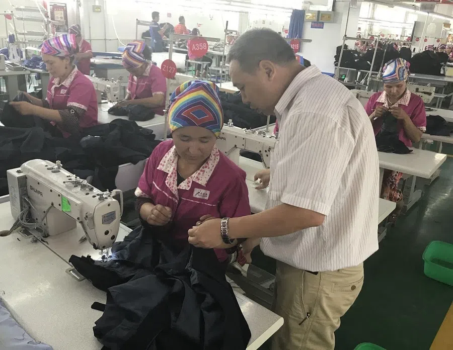 A supervisor from Shenzhen teaching a Uighur worker in a clothing factory in Kashgar, Xinjiang, on 1 August 2017. (Chen Xiangming)