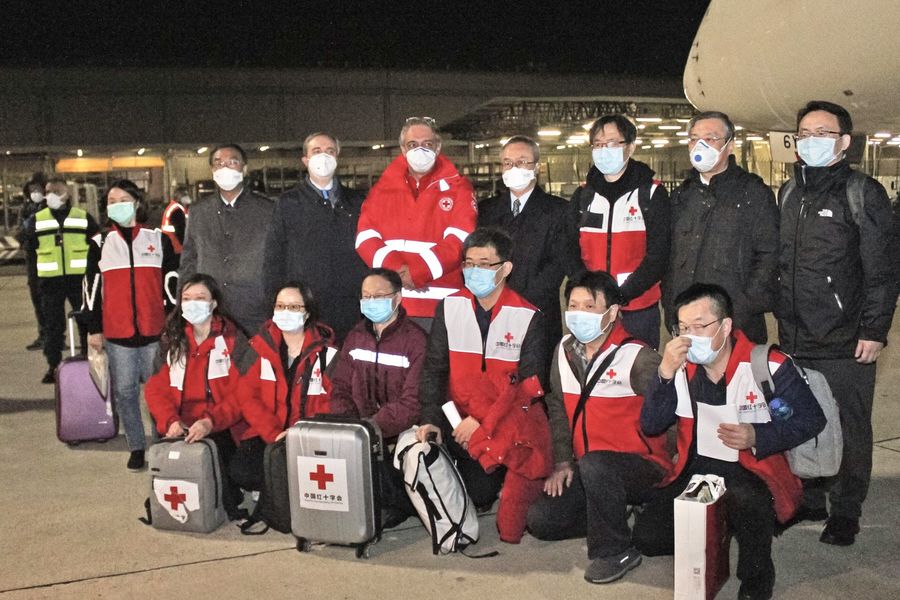 This photo provided by Italian news agency Ansa on 13 March 2020 shows Chinese medics posing for a group photo after landing on a China Eastern flight on 13 March at Rome's Fiumicino international airport from Shanghai, bringing medical aid to help fight the new coronavirus in Italy. (STRINGER/ANSA/AFP)