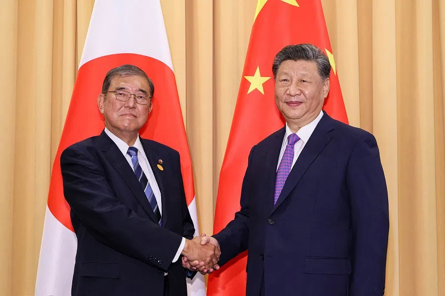 This handout photo taken on 15 November 2024 and received from Japan’s Cabinet Public Relations Office shows Japan’s Prime Minister Shigeru Ishiba (L) shaking hands with China’s President Xi Jinping (R) during their meeting on the sidelines of the Asia-Pacific Economic Cooperation summit in Lima, Peru. (Handout/Cabinet Public Relations Office/AFP)