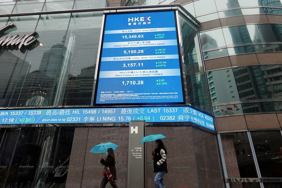People walk past screens displaying the Hang Seng stock index and stock prices outside the Exchange Square in Hong Kong, China, on 23 January 2024. (Joyce Zhou/Reuters)