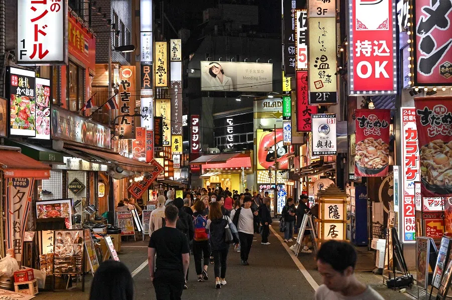 This photo taken on 20 October 2024 shows people making their way through a popular street filled with bars and restaurants in the Shinjuku district of central Tokyo. (Richard A. Brooks/AFP)