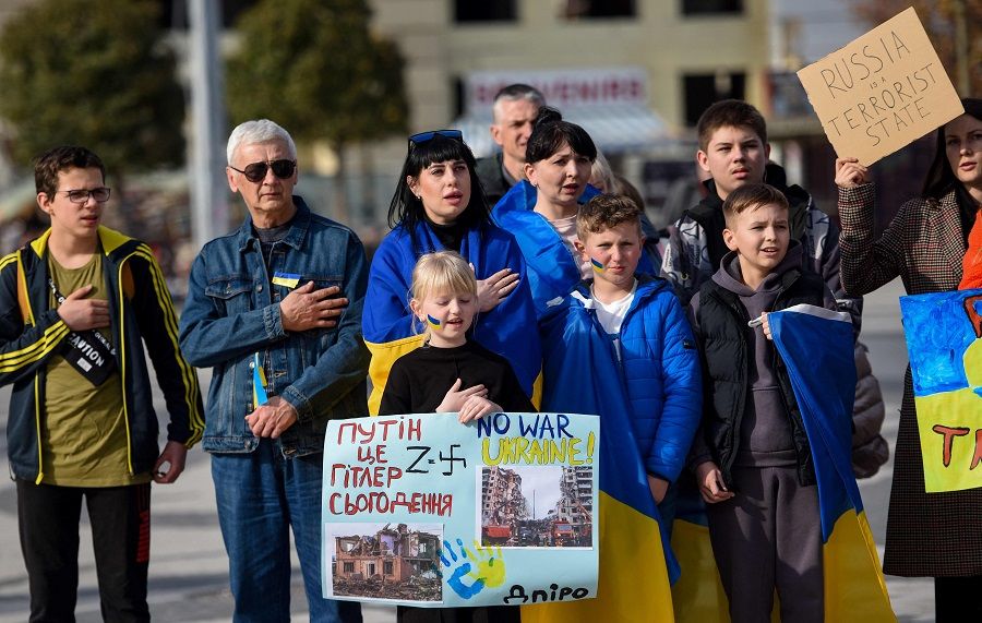 People hold a slogan reading in Macedonian "Putin, the Hitler today" as they take part in a rally to mark the first anniversary of the Russian invasion of Ukraine in Skopje, North Macedonia, on 24 February 2023. (Robert Atanasovski/AFP)