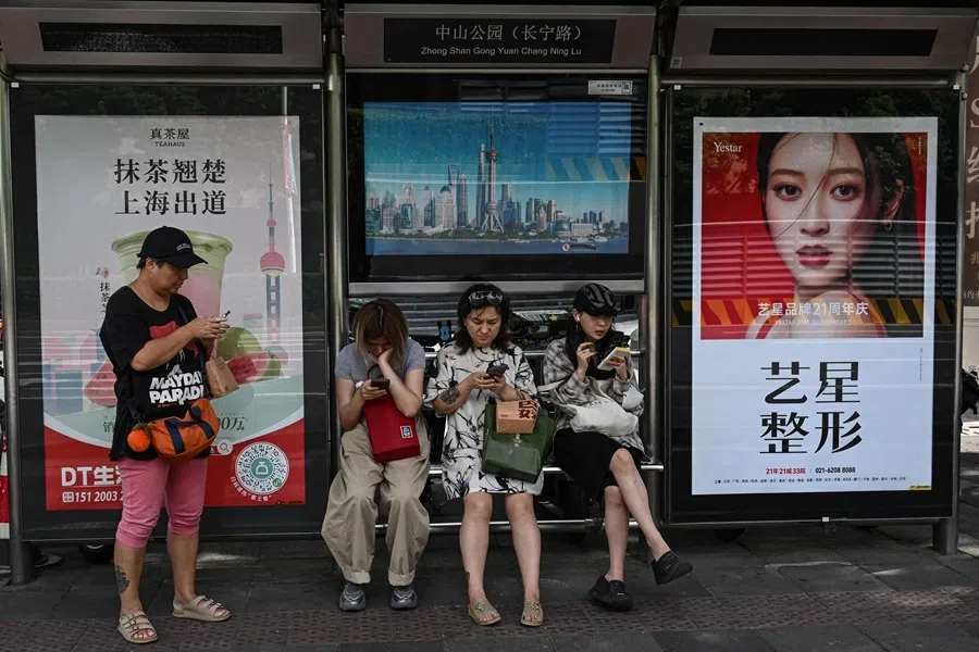 People wait for buses at a bus station on a street in Shanghai on 15 September 2026.