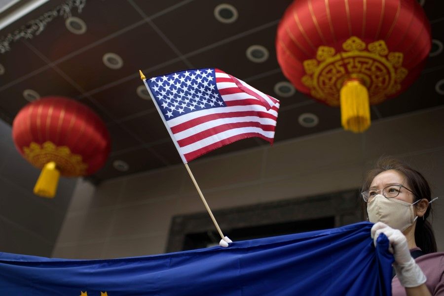 A protester holds a US flag outside of the Chinese consulate in Houston on 24 July 2020, after the US State Department ordered China to close the consulate. (Mark Felix/AFP)