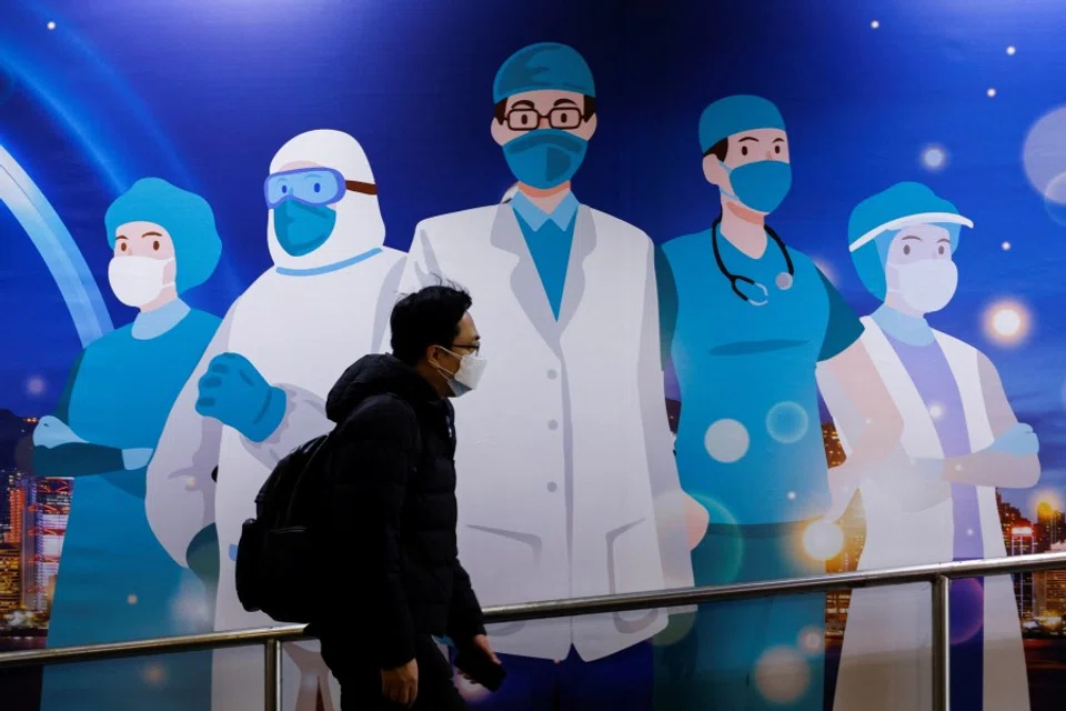 A man wearing a face mask walks past an advertisement to support medical professionals, following the Covid-19 outbreak, in Hong Kong, China, 24 February 2022. (Tyrone Siu/Reuters)