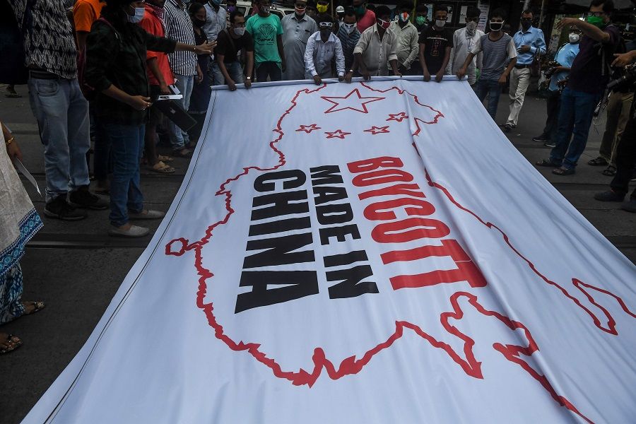 Congress party supporters hold a flag displaying the country and flag of China along with an inscription reading 'Boycott Made in China' during an anti-China demonstration in Kolkata on 18 June 2020. (Dibyangshu Sarkar/AFP)