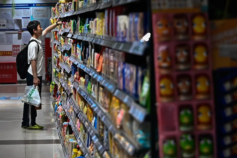 A boy picks a product from a shelf at a supermarket in Beijing on 15 April 2025. (Pedro Pardo/AFP)
