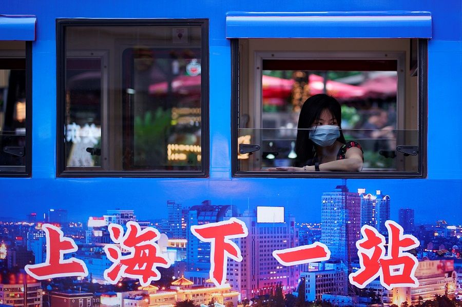 A woman wearing a face mask is seen on a tourist electric car at a shopping area in Shanghai, China, on 16 June 2020. (Aly Song/Reuters)