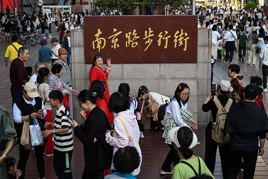 People are seen on the Nanjing pedestrian street in the Huangpu district, in Shanghai, on 30 March 2024. (Hector Retamal/AFP)