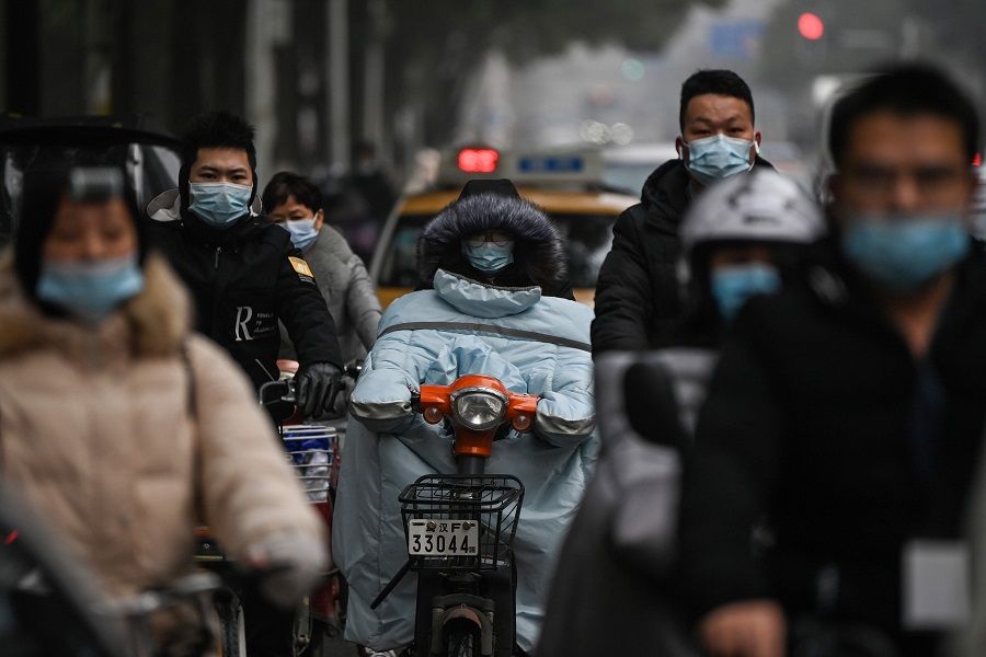 Mask-clad commuters ride on a road in Wuhan, Hubei province, China, on 28 January 2021. (Hector Retamal/AFP)